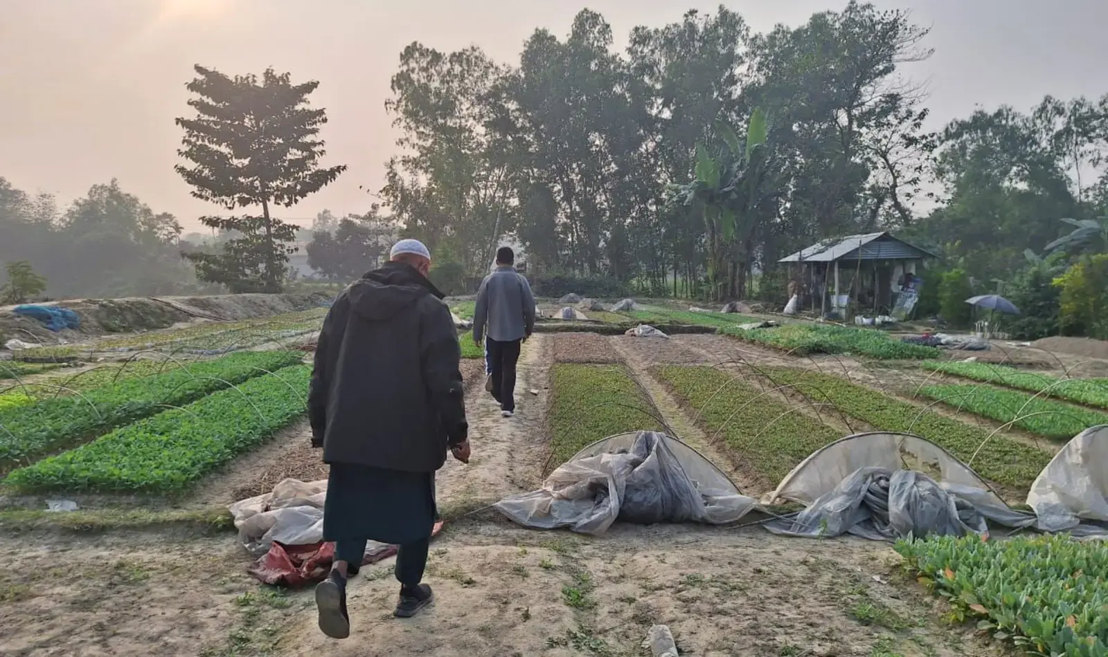 Two people walking through a rural production site in Bangladesh