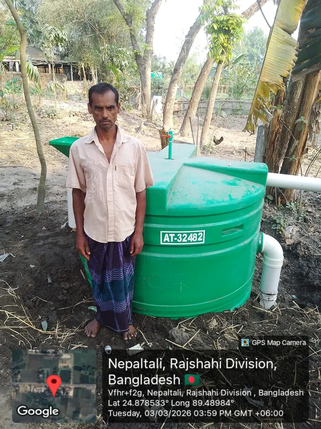 Man standing beside a green household biodigester